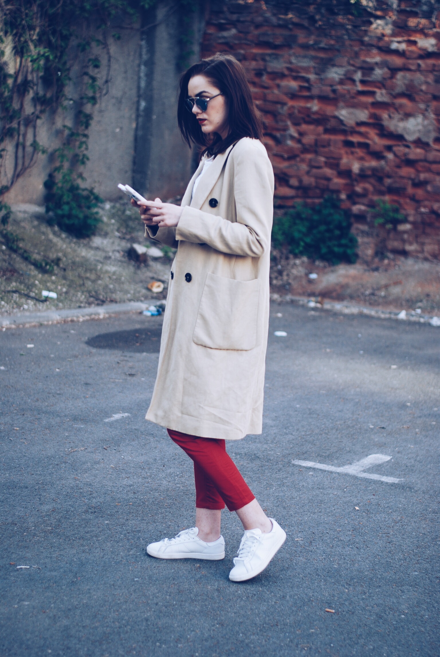 Trench coat, white blouse, so real sunglasses, red trousers, white sneakers, leather bag by Andreea Birsan