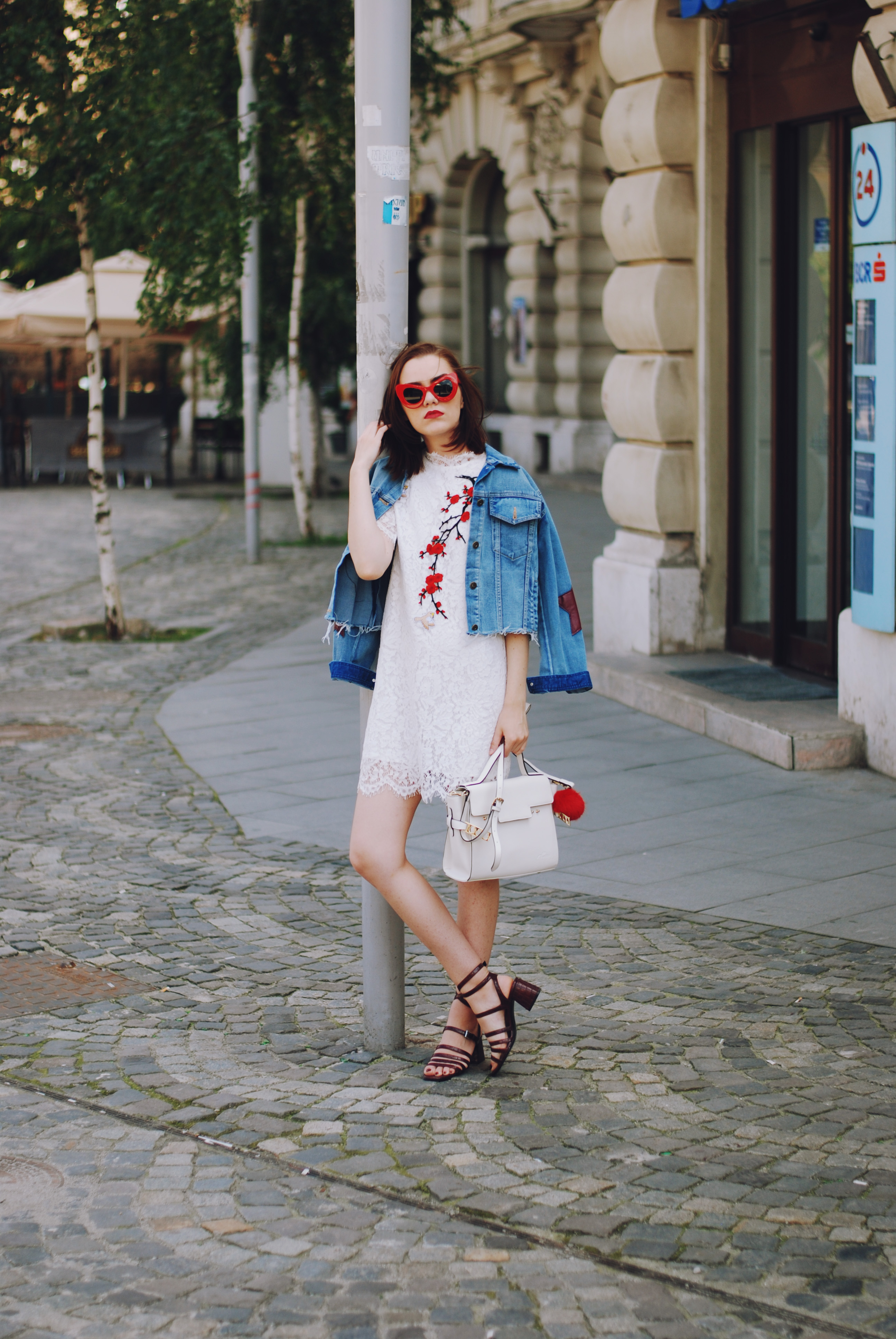 Embroidered white lace dress, red sunglasses, denim jacket, strappy sandals, white crossbody bag, red pom pom. cute summer outfit, Andreea Birsan