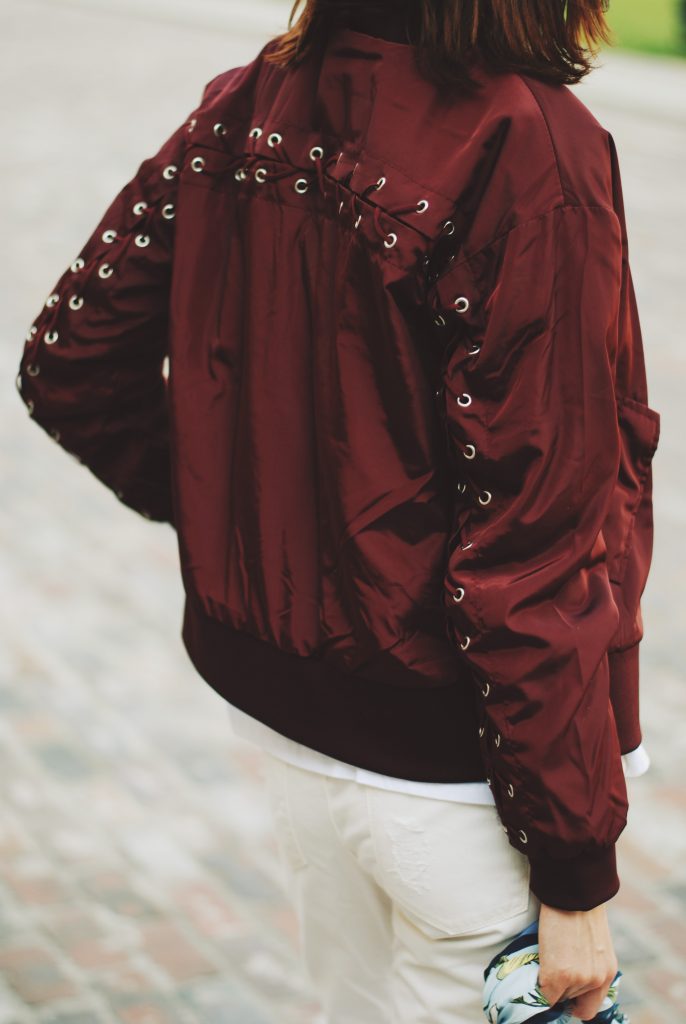 Lace up burgundy bomber jacket, white jeans, strappy sandals, white crossbody bag, sunglasses, fall outfit idea, Andreea Birsan