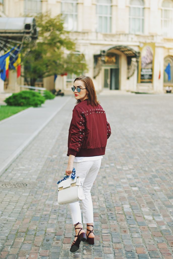 Lace up burgundy bomber jacket, white jeans, strappy sandals, white crossbody bag, sunglasses, fall outfit idea, Andreea Birsan