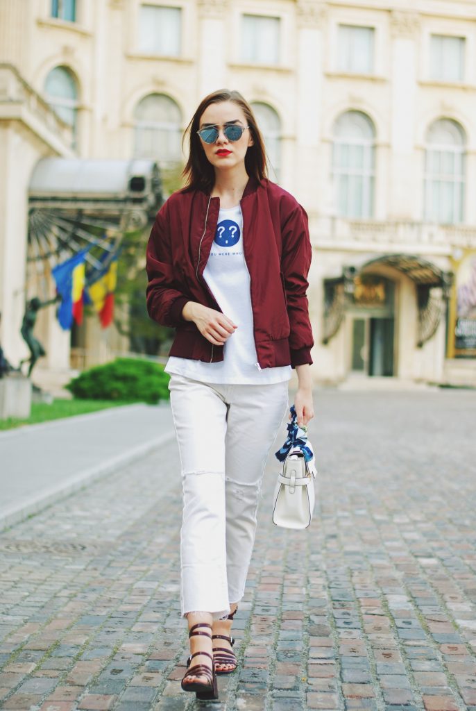 Lace up burgundy bomber jacket, white jeans, strappy sandals, white crossbody bag, sunglasses, fall outfit idea, Andreea Birsan