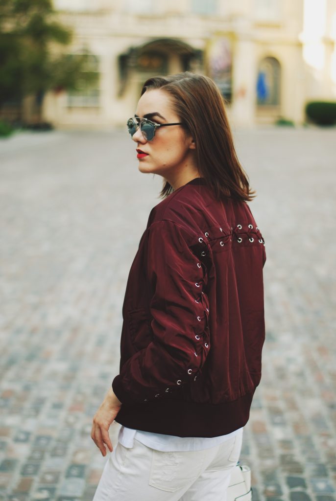 Lace up burgundy bomber jacket, white jeans, strappy sandals, white crossbody bag, sunglasses, fall outfit idea, Andreea Birsan