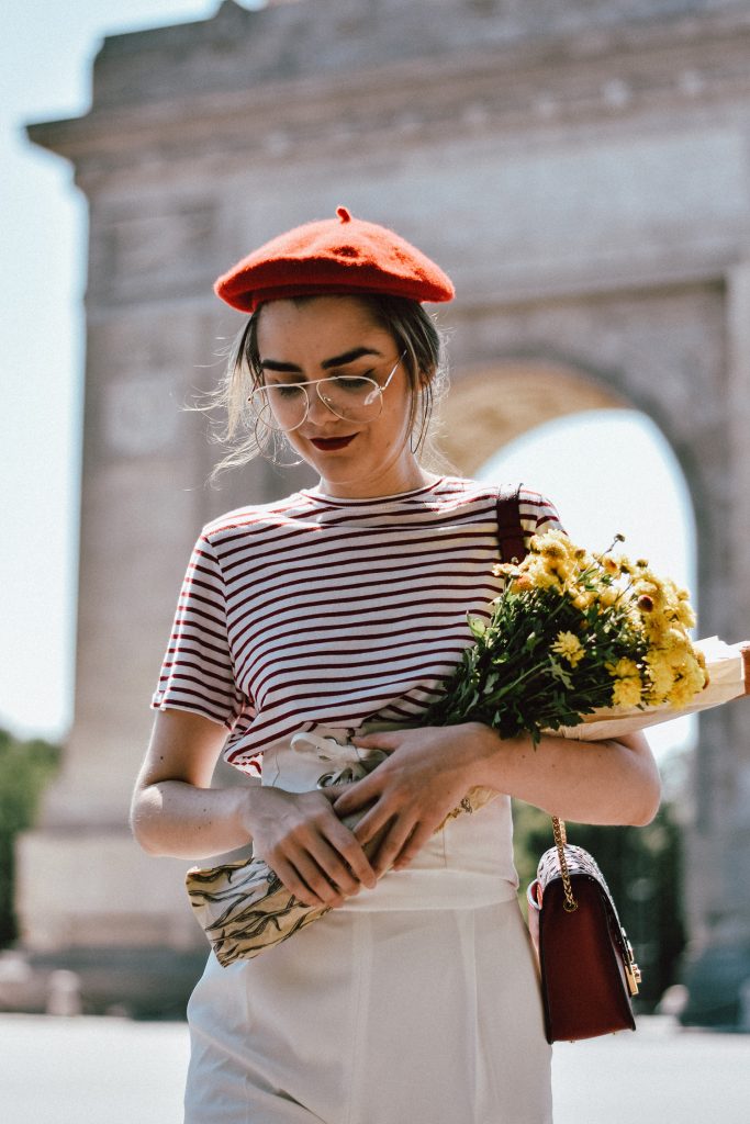 White wide leg pants zara, mango stripe t-shirt, urban outfitters striped tee, asos red beret, forever21 white lace up corset, furla red bag, furla ruby red lace trim metropolis shoulder bag, furla metropolis in red, ray ban aviator clear lens glasses, gucci ace heart embroidered sneakers, andreea birsan, couturezilla, cute summer outfit inspiration, how to look Parisian chic, European summer street style inspiration for women 2017, pinterest chic outfit ideas for woman, summer outfit ideas, summer ootd inspiration, outfit of the day, ootd, fashion icon, style inspiration, fashionista, fashion inspiration, style inspo, what to wear in summer, how to look French, chic on a budget, zara outfit, mango, topshop, asos, river island, forever 21, urban outfitters, how to mix high end pieces with luxury ones, zara and Gucci, how to look chic when not wearing a dress, outfit alternatives for summer, tomboy chic, minimal outfit, tumblr girls photos, pictures, happy girl, women, smart casual outfits, the best outfit ideas 2017, what to wear when you don’t feel inspired, summer in Europe, weekend attire, uniform, French women in summer, European outfit ideas 2017, minimal chic outfit, how to stand out, the best outfit ideas for summer, the sunglasses you have seen everywhere on Instagram, glasses, uk fashion blogger, united kingdom, uk fashion blog, fashion and travel blog, Europe, women with style, street style, summer fashion trends 2017, silver hoop earrings, low bun, classy bun, red lipstick, fresh flowers, how to wear palazzo trousers, palazzo pants, wide leg trousers, how to make wide leg trousers look even chicer, parisian chic, red and white summer outfit 2017