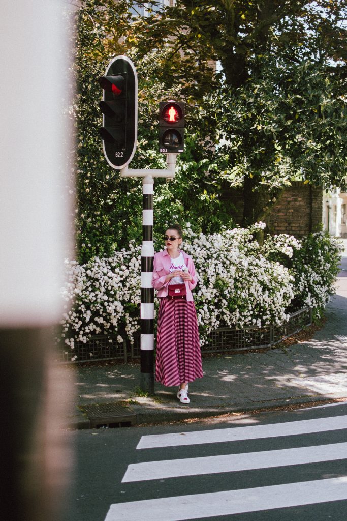 Striped mesh pink and purple skirt, pink cropped cotton jacket, gucci ace sneakers, tshirt, andreea birsan, couturezilla, cute summer outfit for 2018, the color combo you should try this summer pink and purple, pink and purple outfit, ankle length stripe pink mesh skirt, maxi mesh effect skirt, pink striped skirt, long skirt, how to wear a maxi skirt, how to wear a long skirt, what shoes to wear with a maxi skirt, gucci ace heart embroidered white sneakers, gucci white trainers, gucci sneakers with hearts, heart breaker white t-shirt, printed t-shirt, white tee, basic tee, basics, graphic t-shirt, cropped pink cotton jacket, cropped pink denim jacket, denim lookalike jacket, micro sunglasses trend, matrix sunglasses, mini sunglasses, small cat eye sunglasses, fanny bag, belt bag, furla metropolis red bag worn as a belt bag, bum bag, red leather bag, red crossbody bag, genuine leather, pink and purple, how to mix pink and purple, blush pink, mesh effect skirt, skirt and t-shirt, andreea birsan in the netherlands, holland, travel diary, den haag, couturezilla travels, travel outfit, traveling girl look, holland, how to look Parisian chic, European summer street style inspiration for women 2017, pinterest chic outfit ideas for woman, summer outfit ideas, summer ootd inspiration, outfit of the day, ootd, fashion icon, style inspiration, fashionista, fashion inspiration, style inspo, what to wear in summer, how to look French, chic on a budget, zara outfit, mango, topshop, asos, river island, forever 21, urban outfitters, how to mix high end pieces with luxury ones, zara and Gucci,outfit alternatives for summer, tomboy chic, minimal outfit, tumblr girls photos, pictures, happy girl, women, smart casual outfits, the best outfit ideas 2017, what to wear when you don’t feel inspired, summer in Europe, weekend attire, uniform, French women in summer, European outfit ideas 2017, minimal chic outfit, how to stand out, the best outfit ideas for summer, the sunglasses you have seen everywhere on Instagram, glasses, uk fashion blogger, united kingdom, uk fashion blog, fashion and travel blog, Europe, women with style, street style, summer fashion trends 2017, best fashion ideas, styling, fall fashion, fall outfit, fall ootd, fall perfect, transitional dressing, best transitional outfit ideas, how to wear statement earrings, dressing for autumn, autumn outfit, winter outfit ideas for work and school 2017