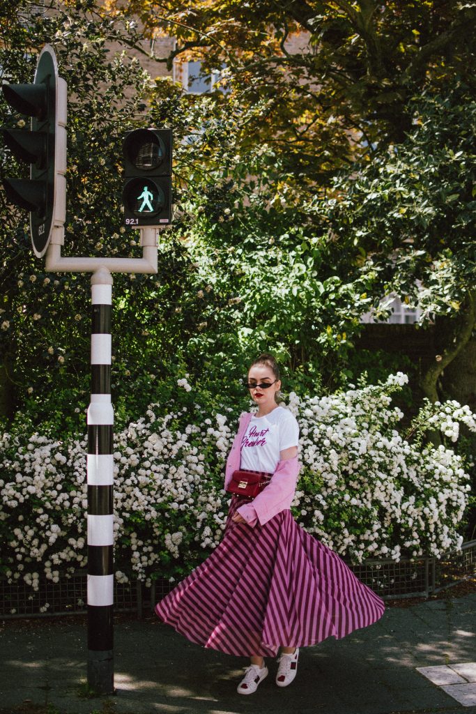 Striped mesh pink and purple skirt, pink cropped cotton jacket, gucci ace sneakers, tshirt, andreea birsan, couturezilla, cute summer outfit for 2018, the color combo you should try this summer pink and purple, pink and purple outfit, ankle length stripe pink mesh skirt, maxi mesh effect skirt, pink striped skirt, long skirt, how to wear a maxi skirt, how to wear a long skirt, what shoes to wear with a maxi skirt, gucci ace heart embroidered white sneakers, gucci white trainers, gucci sneakers with hearts, heart breaker white t-shirt, printed t-shirt, white tee, basic tee, basics, graphic t-shirt, cropped pink cotton jacket, cropped pink denim jacket, denim lookalike jacket, micro sunglasses trend, matrix sunglasses, mini sunglasses, small cat eye sunglasses, fanny bag, belt bag, furla metropolis red bag worn as a belt bag, bum bag, red leather bag, red crossbody bag, genuine leather, pink and purple, how to mix pink and purple, blush pink, mesh effect skirt, skirt and t-shirt, andreea birsan in the netherlands, holland, travel diary, den haag, couturezilla travels, travel outfit, traveling girl look, holland, how to look Parisian chic, European summer street style inspiration for women 2017, pinterest chic outfit ideas for woman, summer outfit ideas, summer ootd inspiration, outfit of the day, ootd, fashion icon, style inspiration, fashionista, fashion inspiration, style inspo, what to wear in summer, how to look French, chic on a budget, zara outfit, mango, topshop, asos, river island, forever 21, urban outfitters, how to mix high end pieces with luxury ones, zara and Gucci,outfit alternatives for summer, tomboy chic, minimal outfit, tumblr girls photos, pictures, happy girl, women, smart casual outfits, the best outfit ideas 2017, what to wear when you don’t feel inspired, summer in Europe, weekend attire, uniform, French women in summer, European outfit ideas 2017, minimal chic outfit, how to stand out, the best outfit ideas for summer, the sunglasses you have seen everywhere on Instagram, glasses, uk fashion blogger, united kingdom, uk fashion blog, fashion and travel blog, Europe, women with style, street style, summer fashion trends 2017, best fashion ideas, styling, fall fashion, fall outfit, fall ootd, fall perfect, transitional dressing, best transitional outfit ideas, how to wear statement earrings, dressing for autumn, autumn outfit, winter outfit ideas for work and school 2017