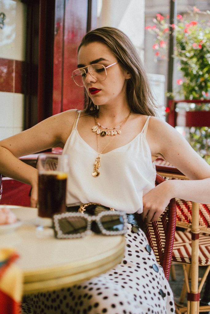 Zara polka dot skirt, white cami top, gucci ace heart sneakers, cherry pom pom straw summer bag, paris, andreea birsan, couturezilla, cute summer outfit ideas 2018, polka dot midi skirt, spaghetti straps white camisole top, mango white, white and black midi skirt, the zara sold out polka dot skirt, basic white cami top, how to wear a midi skirt, what to wear with a midi polka dot skirt, how to style a polka dot skirt, how to wear a polka dot skirt, gucci trainers, gucci ace heart embroidered sneakers, white trainers, heart embroidery, white leather shoes, parisian cafe, skirt and sneakers, shell accessories, shell necklaces, gold layered necklaces, gucci inspired embellished square sunglasses, 90s sunglasses, black sunglasses, printed silk scarf, clear lens aviator glasses, zara glasses, the geeky glasses trend, the clear lens glasses trend you’ve seen on instagram, popular glasses, gucci 90s inspired square embellished sunglasses with rhinestones, pom pom summer bag, straw bag, asos sold out summer bag, raffia tote bag, statement summer bag, how to look Parisian chic, European summer street style inspiration for women 2017, pinterest chic outfit ideas for woman, summer outfit ideas, summer ootd inspiration, outfit of the day, ootd, fashion icon, style inspiration, fashionista, fashion inspiration, style inspo, what to wear in summer, how to look French, chic on a budget, zara outfit, mango, topshop, asos, river island, forever 21, urban outfitters, how to mix high end pieces with luxury ones, zara and Gucci,outfit alternatives for summer, tomboy chic, minimal outfit, tumblr girls photos, pictures, happy girl, women, smart casual outfits, the best outfit ideas 2017, what to wear when you don’t feel inspired, summer in Europe, weekend attire, uniform, French women in summer, European outfit ideas 2017, minimal chic outfit, how to stand out, the best outfit ideas for summer, the sunglasses you have seen everywhere on Instagram, glasses, uk fashion blogger, united kingdom, uk fashion blog, fashion and travel blog, Europe, women with style, street style, summer fashion trends 2017, best fashion ideas, styling, fall fashion, fall outfit, fall ootd, fall perfect, transitional dressing, best transitional outfit ideas, how to wear statement earrings, dressing for autumn, autumn outfit, winter outfit ideas for work and school 2017