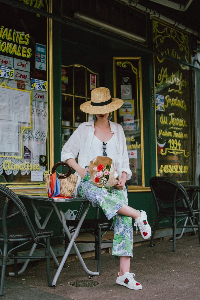 Zara floral print pants, flower print culottes, why you should wear floral print trousers, floral culottes, green blue and white pants, white cami top, mango camisole top, zara button down white linen shirt, boyfriend shirt, oversized shirt, gucci ace heart embroidered sneakers, gucci white sneakers, white leather sneakers, gucci trainers, h&m straw boater hat, summer straw bag with wooden handle, mini bag, the best summer bags, micro cat eye sunglasses, andreea birsan, couturezilla, cute summer outfit ideas 2018, sunnies, retro sunglasses, the asos sold out micro sunglasses, statement floral earrings, zara flower earrings, striped silk scarf, parisian cafe, andreea birsan travels to france, lille france, travel diary, what to wear when you travel to europe in summer, the perfect european summer outfit, how to wear a white shirt in different ways, handmade bags, bag made in thailand, wicker bag, natural fabric bag, how to wear florals, what to wear with floral printed pants, how to pull off culottes, what shoes to wear with culottes, tourist outfit, how to look Parisian chic, European summer street style inspiration for women 2017, pinterest chic outfit ideas for woman, summer outfit ideas, summer ootd inspiration, outfit of the day, ootd, fashion icon, style inspiration, fashionista, fashion inspiration, style inspo, what to wear in summer, how to look French, chic on a budget, zara outfit, mango, topshop, asos, river island, forever 21, urban outfitters, how to mix high end pieces with luxury ones, zara and Gucci,outfit alternatives for summer, tomboy chic, minimal outfit, tumblr girls photos, pictures, happy girl, women, smart casual outfits, the best outfit ideas 2017, what to wear when you don’t feel inspired, summer in Europe, weekend attire, uniform, French women in summer, European outfit ideas 2017, minimal chic outfit, how to stand out, the best outfit ideas for summer, the sunglasses you have seen everywhere on Instagram, glasses, uk fashion blogger, united kingdom, uk fashion blog, fashion and travel blog, Europe, women with style, street style, summer fashion trends 2017, best fashion ideas, styling, fall fashion, fall outfit, fall ootd, fall perfect, transitional dressing, best transitional outfit ideas, how to wear statement earrings, dressing for autumn, autumn outfit, winter outfit ideas for work and school 2017