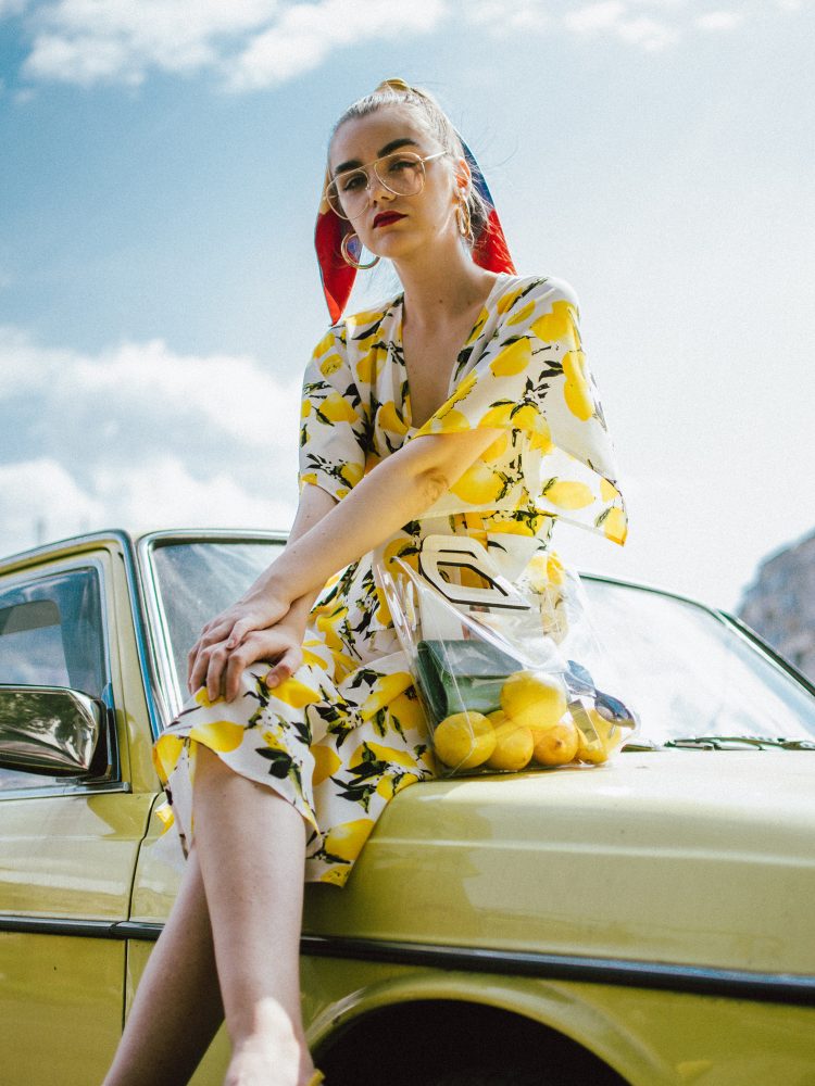 Lemon print midi dress, yellow slingback shoes, transparent tote bag, andreea birsan, couturezilla, cute summer outfit ideas 2018, lemon print dress, tie front lemon print dress, sicialian print, why you should wear a fruit print this summer, the prints that are hot right now, the best holiday dress, what you should wear on a summer holiday, warm weather midi dress, yellow and white midi tie front dress, top knot dress, vinyl tote bag, staud inspired bag, how to wear yellow, lemons, fruit print clothing, d&g inspired print dress, lemon printed dress, how to wear a midi dress, what shoes to wear with a midi dress, yellow suede slingback shoes, yellow kitten heel shoes, slingbacks, yellow shoes, how to pull off yellow shoes, the transparent bag trend, pcv bag, celine inspired plastic bag trend, the best bags from mango, silk striped scarf, scarf in hair, how to style a scarf in your ponytail, how to wear a scarf, best summer dresses, how to look Parisian chic, European summer street style inspiration for women 2017, pinterest chic outfit ideas for woman, summer outfit ideas, summer ootd inspiration, outfit of the day, ootd, fashion icon, style inspiration, fashionista, fashion inspiration, style inspo, what to wear in summer, how to look French, chic on a budget, zara outfit, mango, topshop, asos, river island, forever 21, urban outfitters, how to mix high end pieces with luxury ones, zara and Gucci,outfit alternatives for summer, tomboy chic, minimal outfit, tumblr girls photos, pictures, happy girl, women, smart casual outfits, the best outfit ideas 2017, what to wear when you don’t feel inspired, summer in Europe, weekend attire, uniform, French women in summer, European outfit ideas 2017, minimal chic outfit, how to stand out, the best outfit ideas for summer, the sunglasses you have seen everywhere on Instagram, glasses, uk fashion blogger, united kingdom, uk fashion blog, fashion and travel blog, Europe, women with style, street style, summer fashion trends 2017, best fashion ideas, styling, fall fashion, fall outfit, fall ootd, fall perfect, transitional dressing, best transitional outfit ideas, how to wear statement earrings, dressing for autumn, autumn outfit, winter outfit ideas for work and school 2017, clear lens aviator glasses, the clear lens glasses trend, geeky glasses, gold hoop earrings